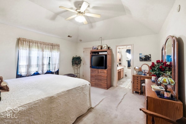 Vaulted ceiling with a ceiling fan, carpeted flooring, and a window with sheer curtains