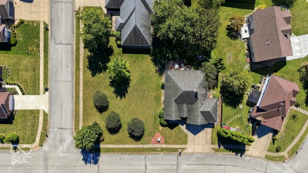 Gabled roofline with asphalt shingles, mature trees, and established landscaping