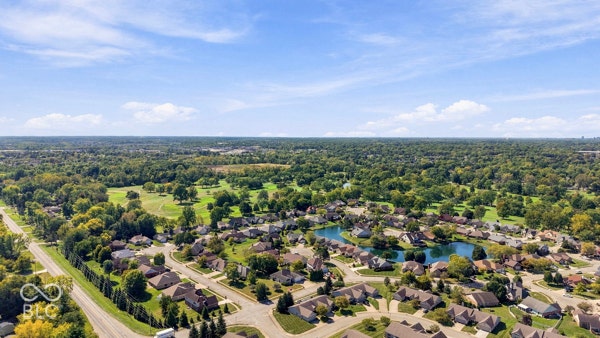 Residential community with mature tree coverage, a golf course, and a large pond