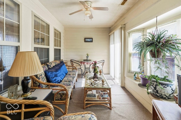 Enclosed sunroom featuring multiple windows, a ceiling fan, and carpeted flooring