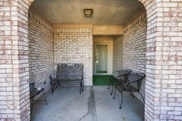 Covered porch entry featuring brick archway and concrete flooring