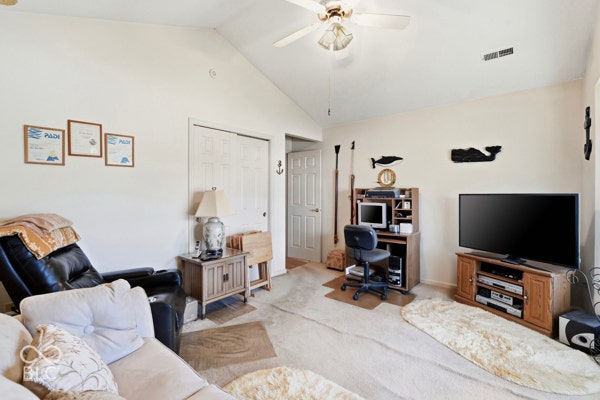 Vaulted ceiling with a ceiling fan light fixture, white interior doors, and neutral wall paint