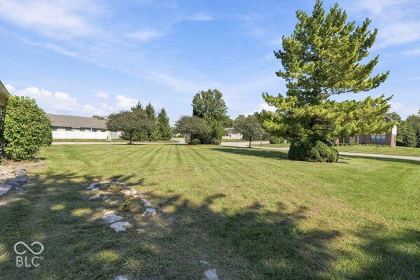 Expansive lawn with mature trees and a stone-lined fire pit