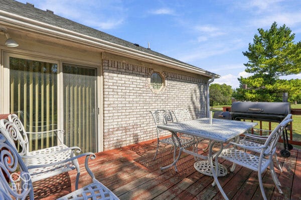 Wood deck with a brick exterior, featuring a sliding glass door and a round accent window