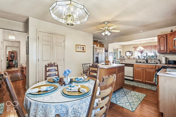 Wood-finish flooring throughout, with a recessed kitchen featuring wood cabinetry and white appliances