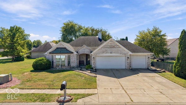Light brick exterior with a prominent two-car garage, pitched roofline, and front yard landscaping