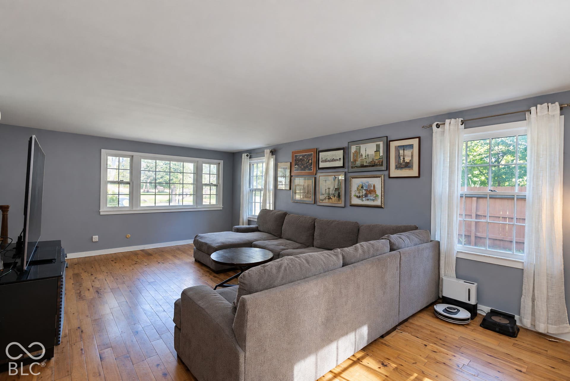 Hardwood flooring throughout, multiple windows providing ample natural light, and a neutral wall color