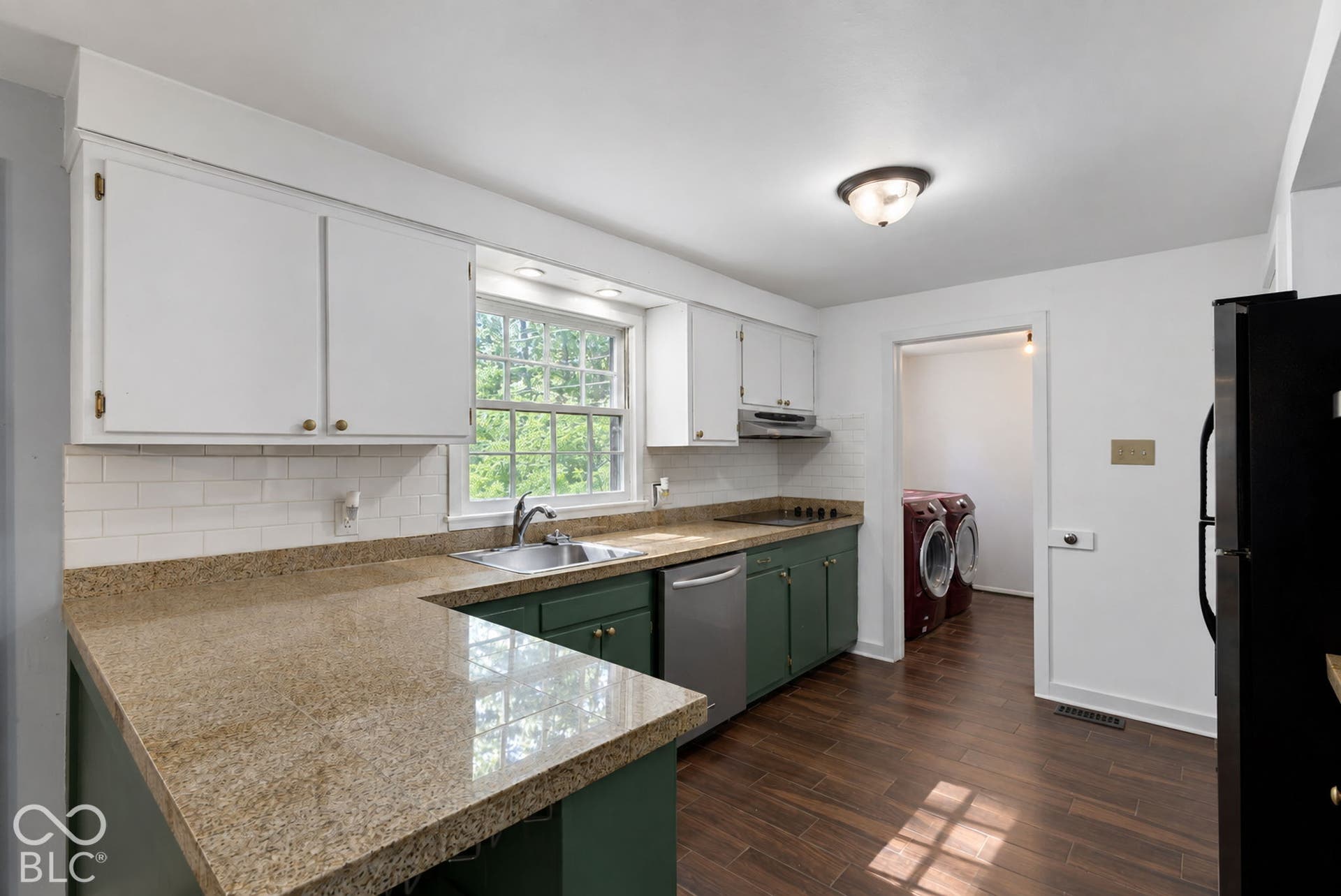 Lovely decorated kitchen, a great space for hosting with a modern white subway tile backsplash, wood-finish flooring, recessed lighting, and stainless-steel dishwasher