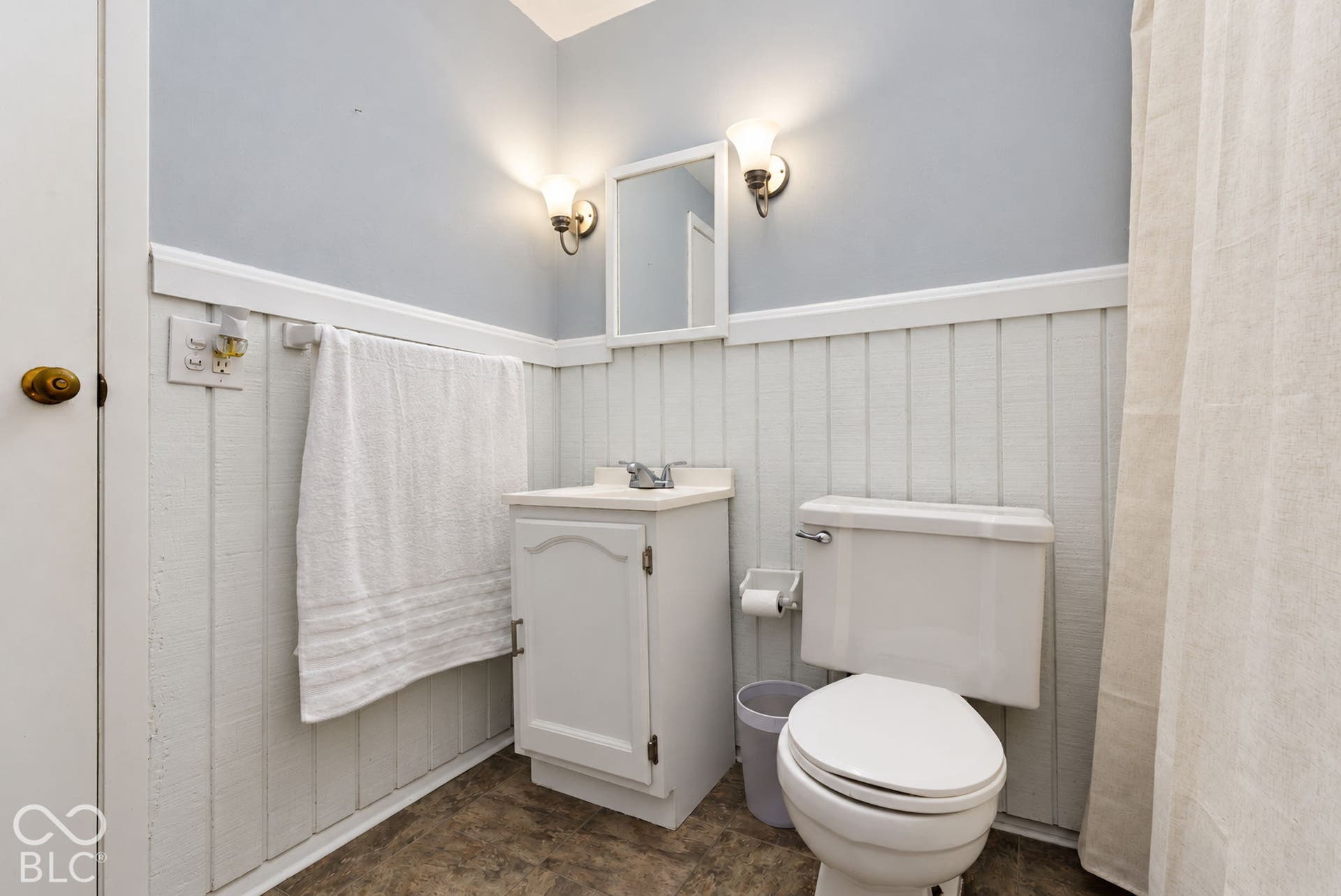 Bathroom featuring white beadboard paneling, a white vanity with integrated sink, and a toilet