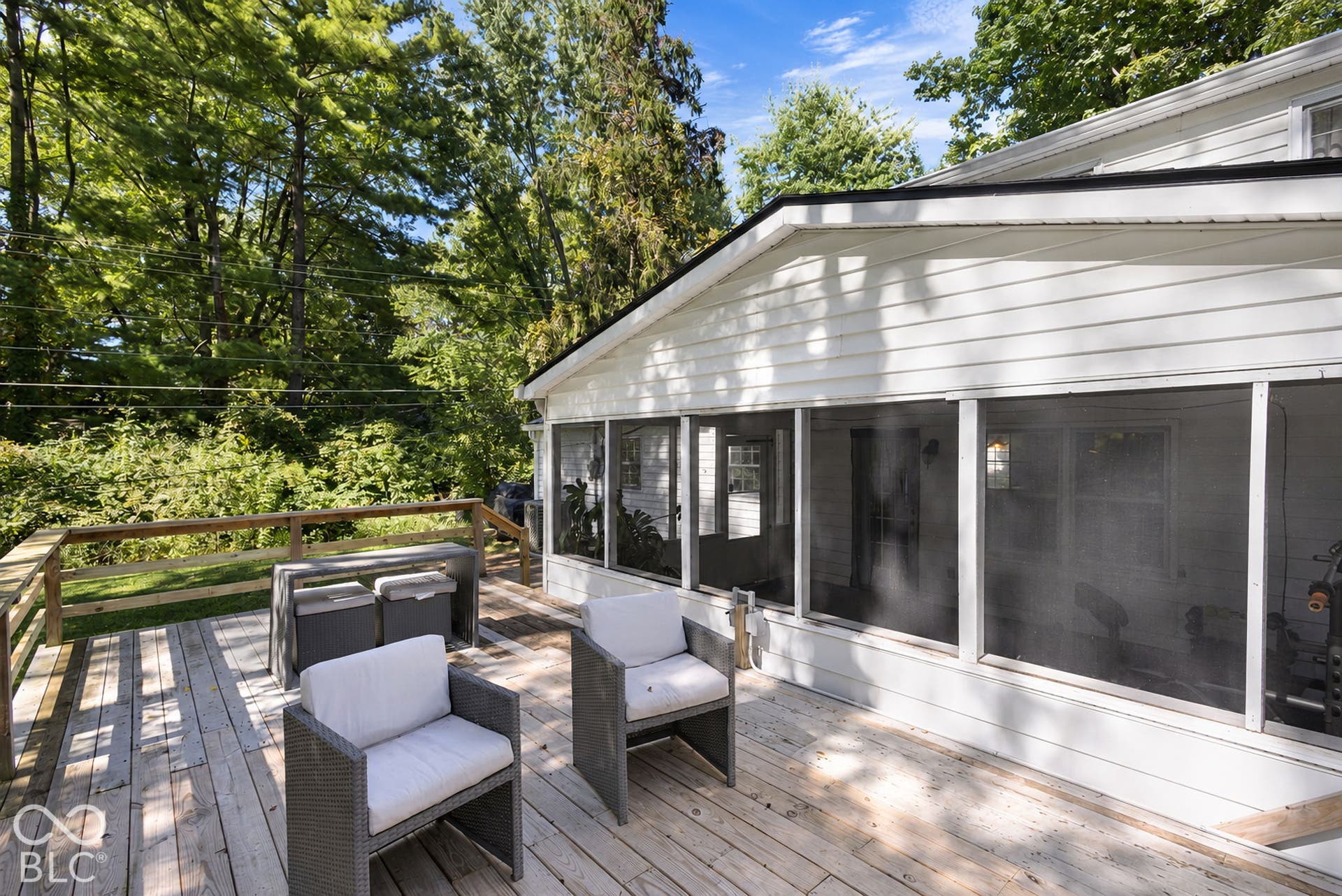 Expansive wood-finish deck with a wood railing and white siding