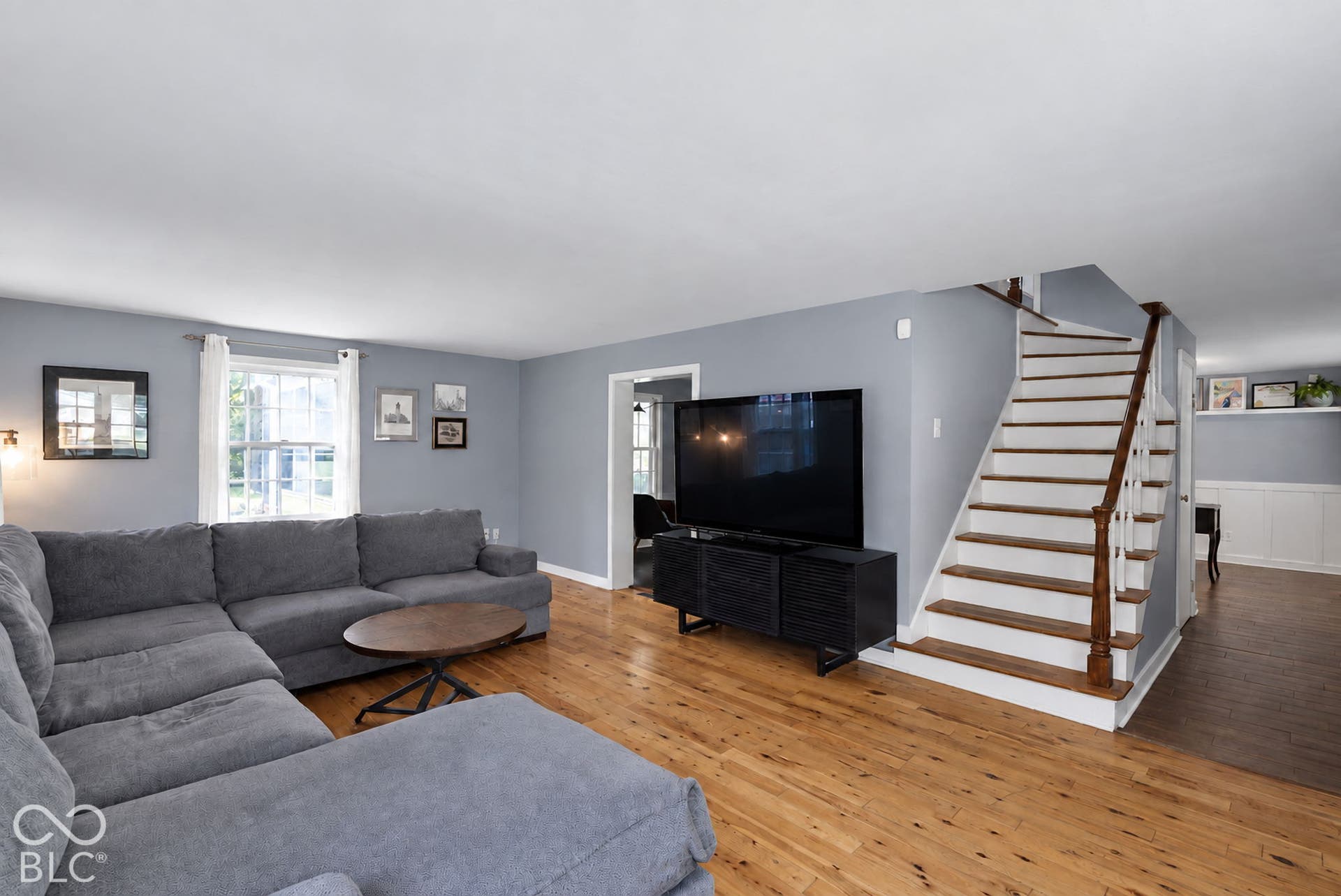 Hardwood flooring, painted interior walls, classic staircase with wood treads and white risers, built-in cabinetry, and window with natural light