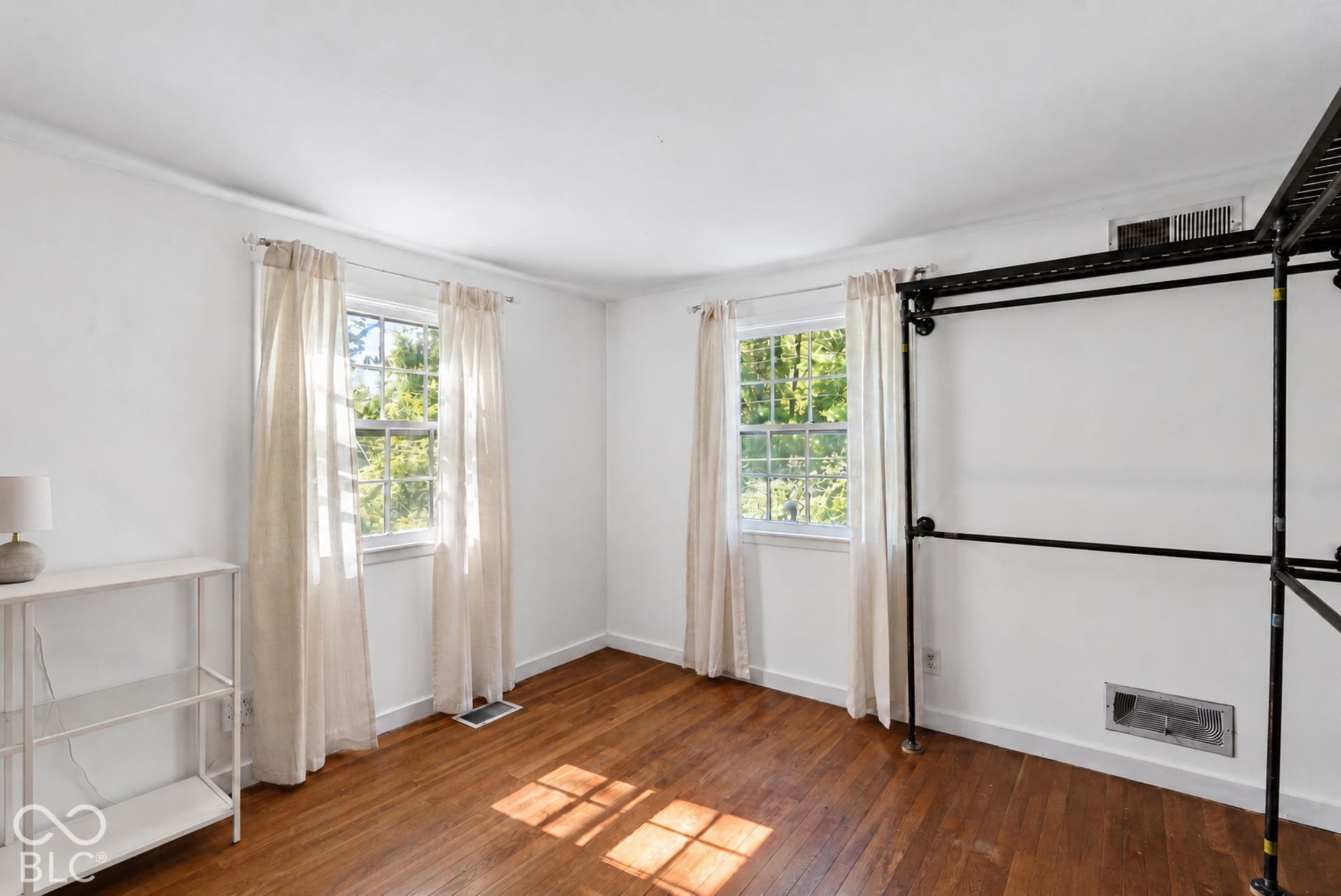 Hardwood flooring throughout, featuring two windows with natural light, white walls, and crown molding