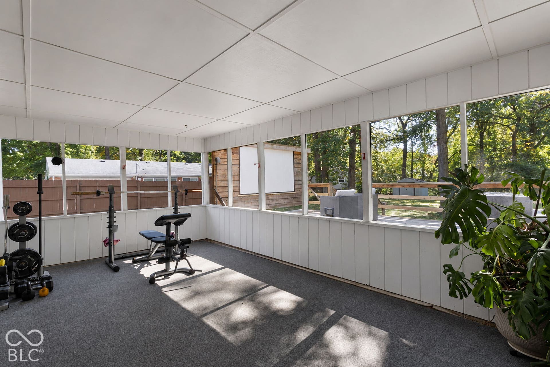 Enclosed sun room is used here as a workout room but serves as a  versatile space for any homeowner that wants to enjoy this picturesque backyard