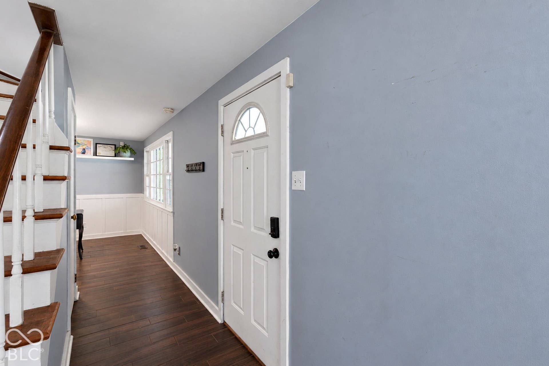 Entryway featuring wood-finish flooring, white wainscoting, and a multi-pane window