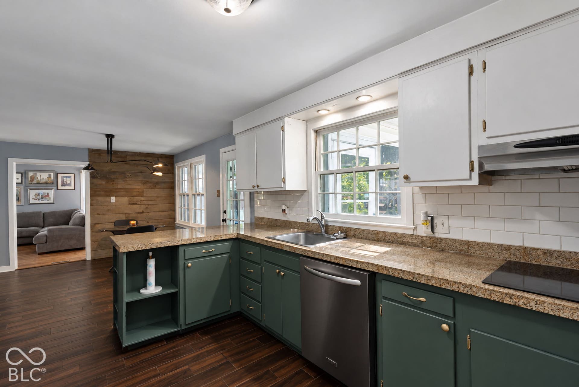 Kitchen featuring two-tone cabinetry with white upper cabinets and deep green lower cabinets, wood-finish flooring, a stainless steel dishwasher, and a subway tile backsplash