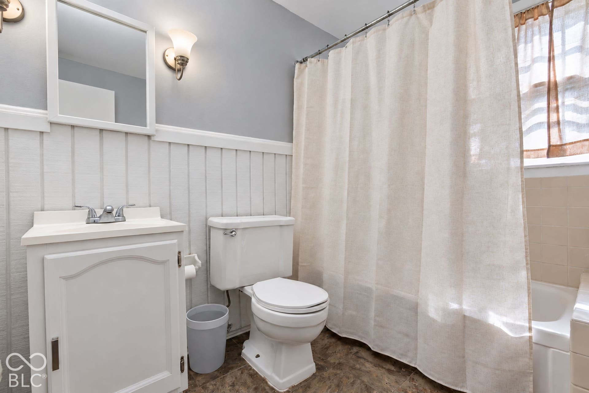 Bathroom featuring a white vanity with integrated sink, chrome-finish faucet, and board and batten wall paneling