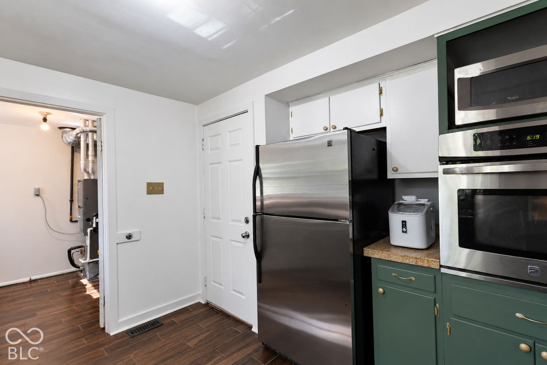 Newer Stainless steel refrigerator, built-in microwave, wall oven, wood-finish flooring, and painted cabinetry