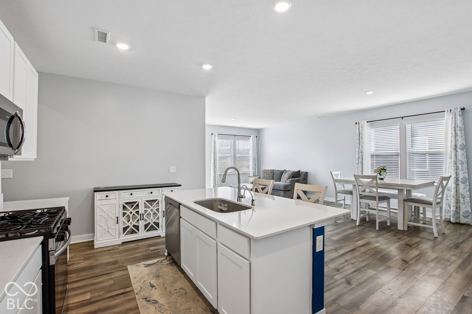Open-concept living area featuring wood-finish flooring, recessed lighting, and a kitchen island with an integrated sink