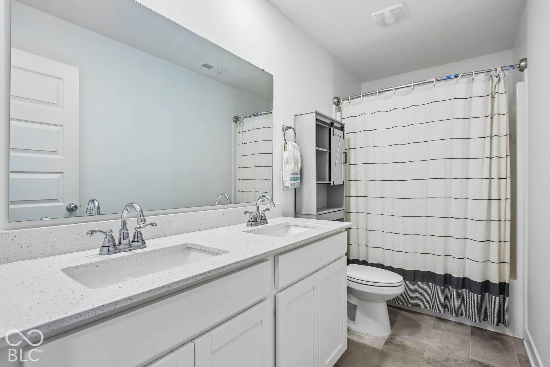 Dual vanity with integrated sinks, polished chrome fixtures, and a white countertop