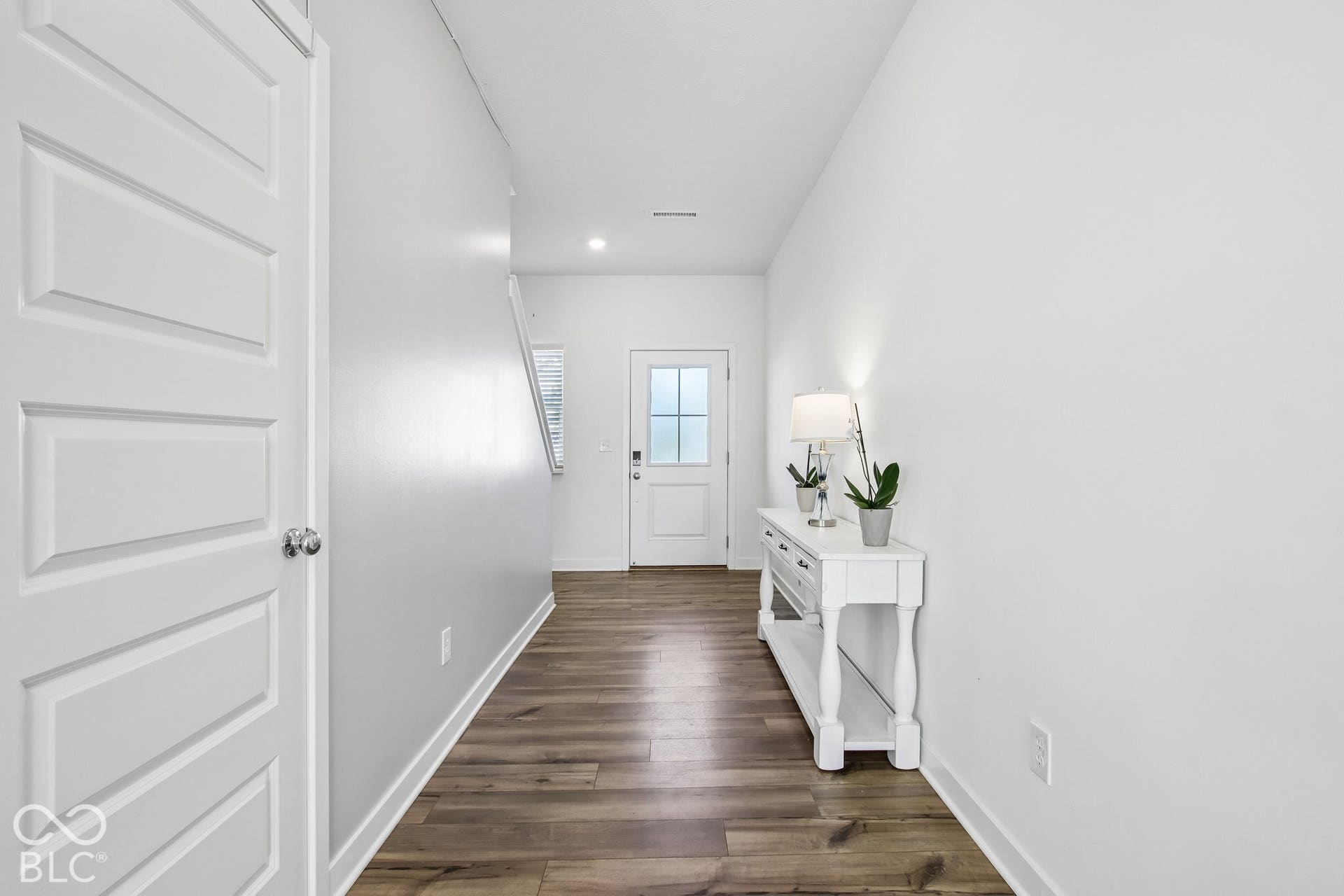 Wood-finish flooring throughout, bright white walls, and a recessed ceiling light
