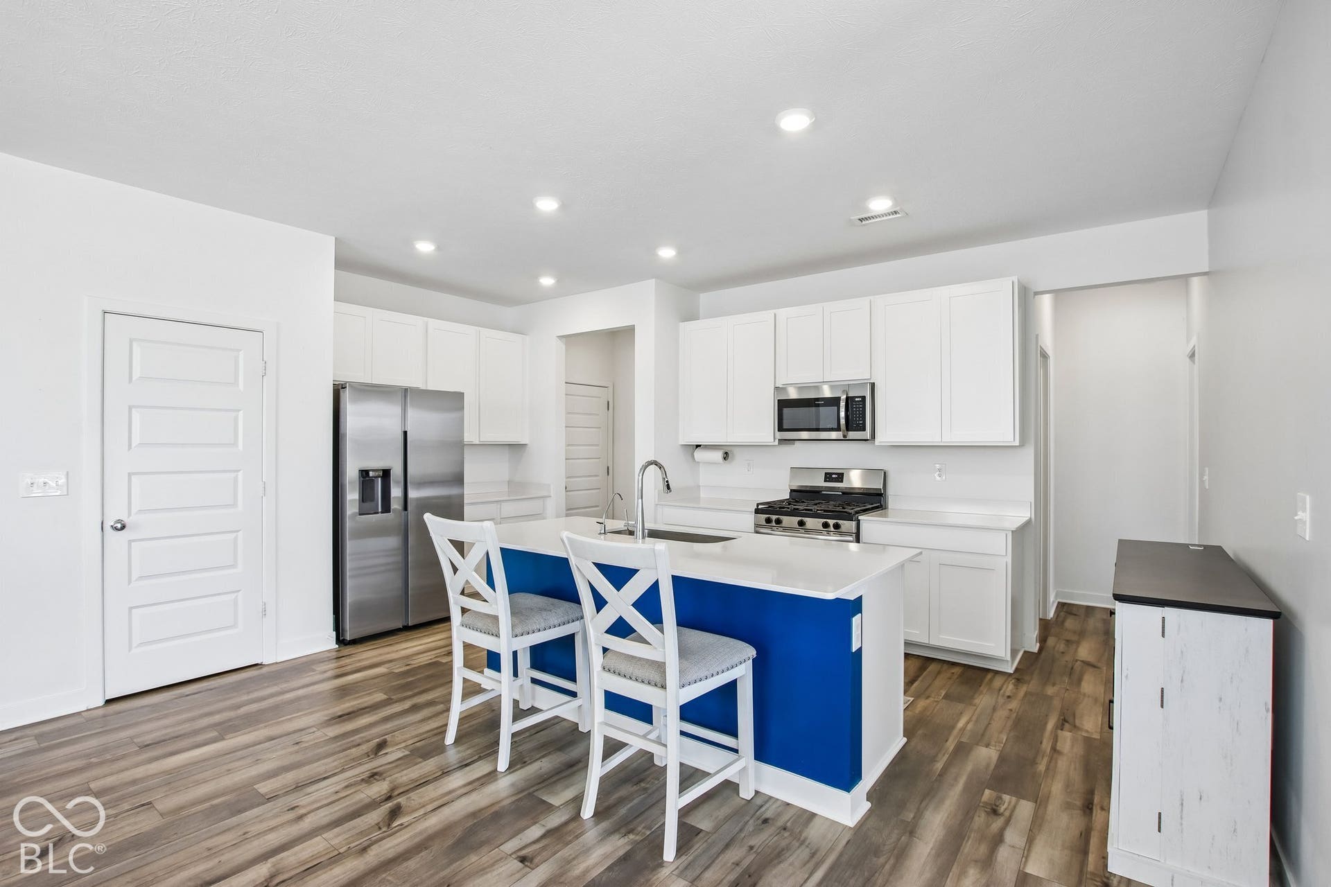 Kitchen featuring wood-finish flooring, white cabinetry, stainless steel appliances, a white countertop, and recessed lighting