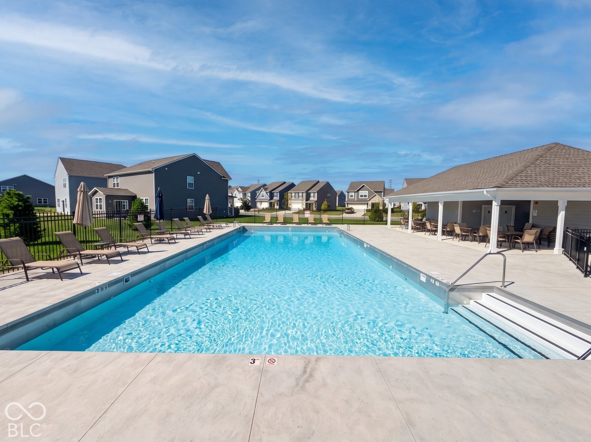 Community swimming pool with an integrated lounge area, a covered outdoor seating structure, and ample deck space