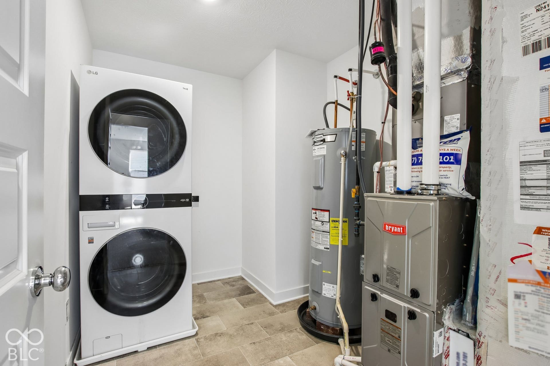 Dedicated utility space featuring stacked laundry appliances, a water heater, and a furnace