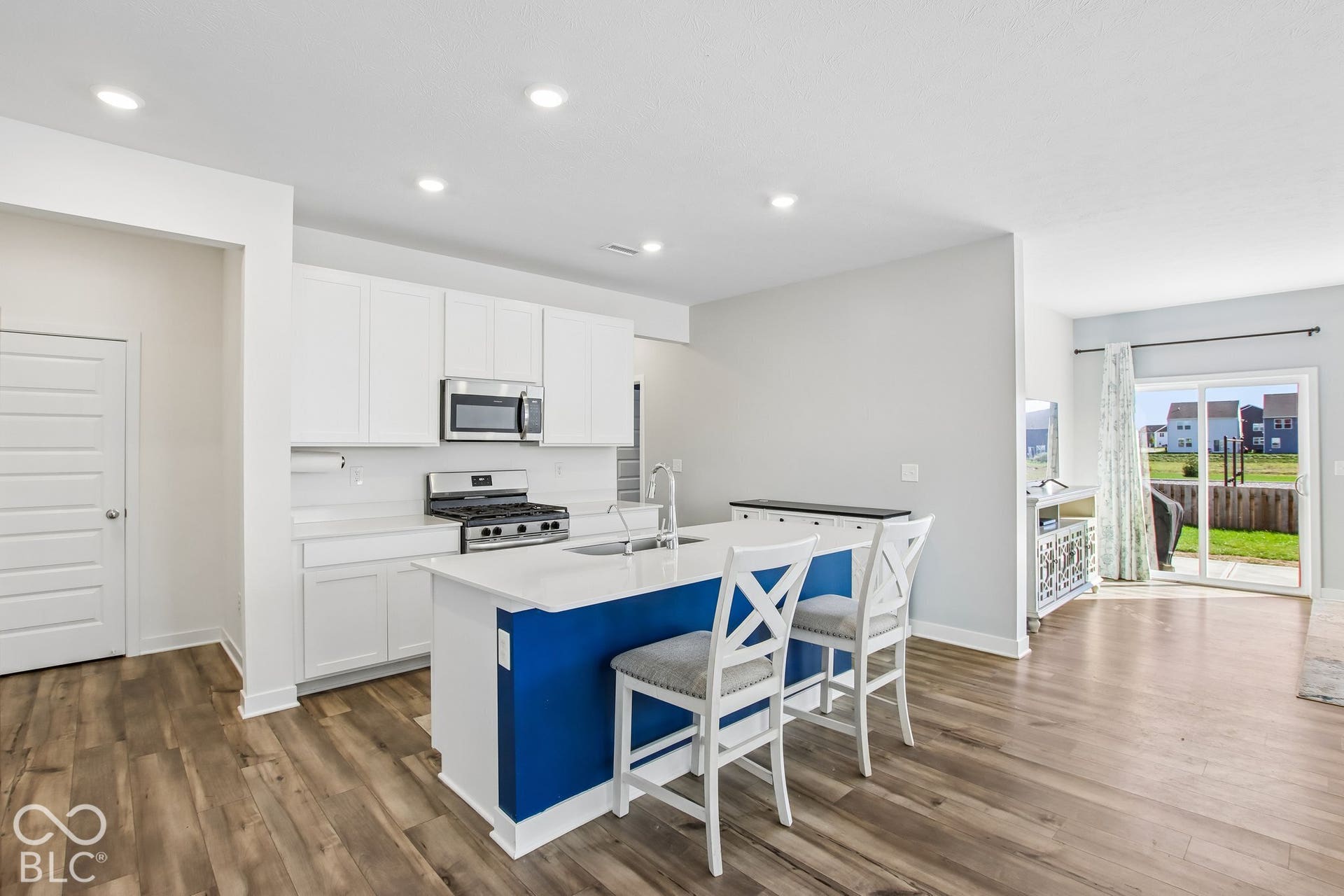 Bright kitchen with white cabinetry, stainless steel appliances, a center island with seating, and wood-finish flooring
