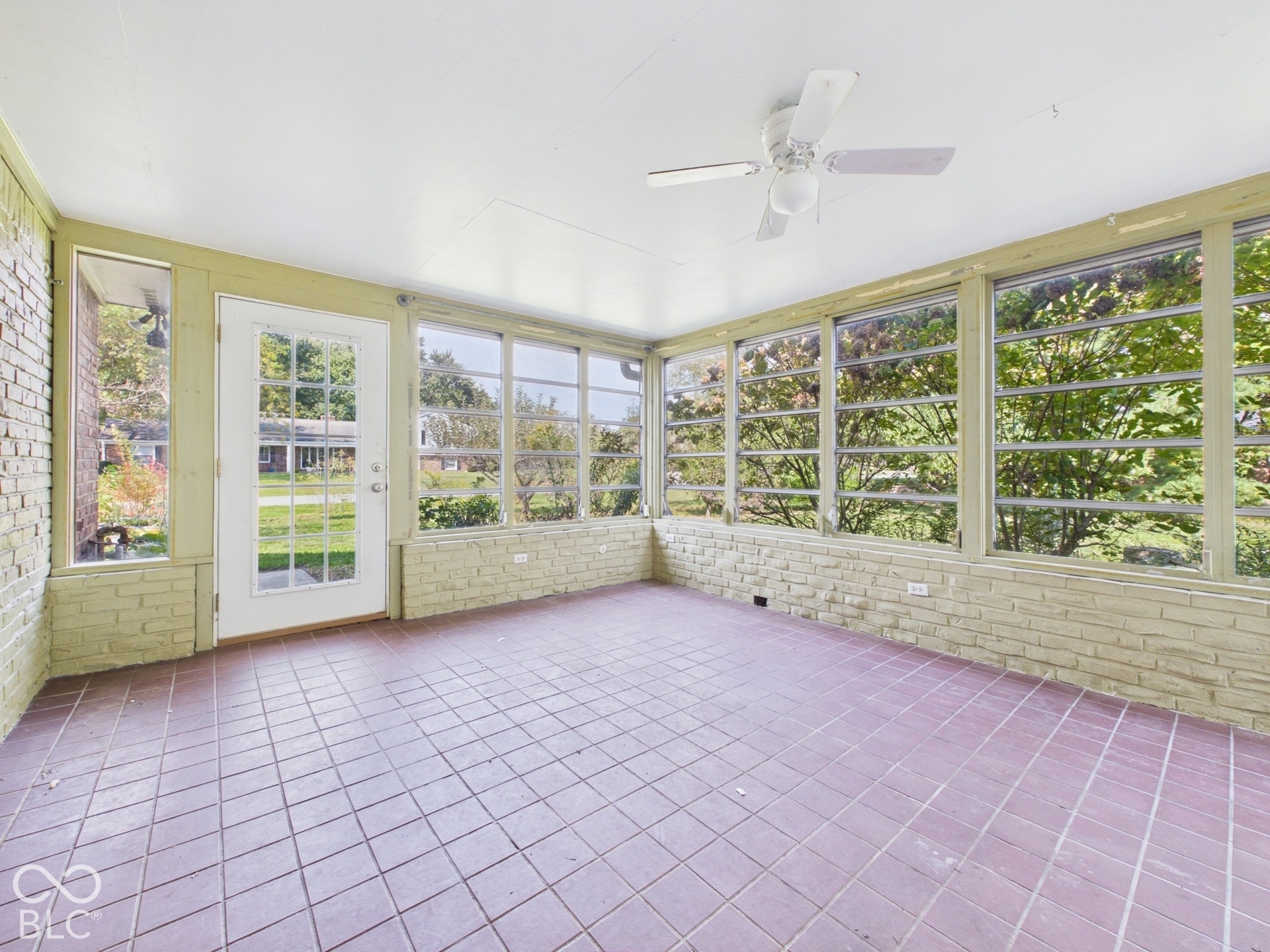 Sunroom with brick half-walls, extensive window coverage, and tile flooring