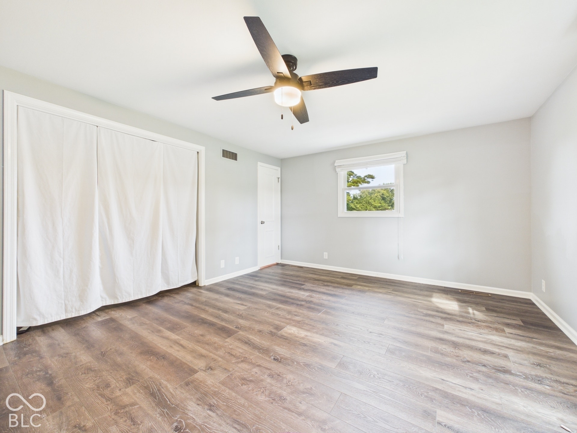 Wood-finish flooring, ceiling fan with integrated lighting, and a single window offering natural illumination