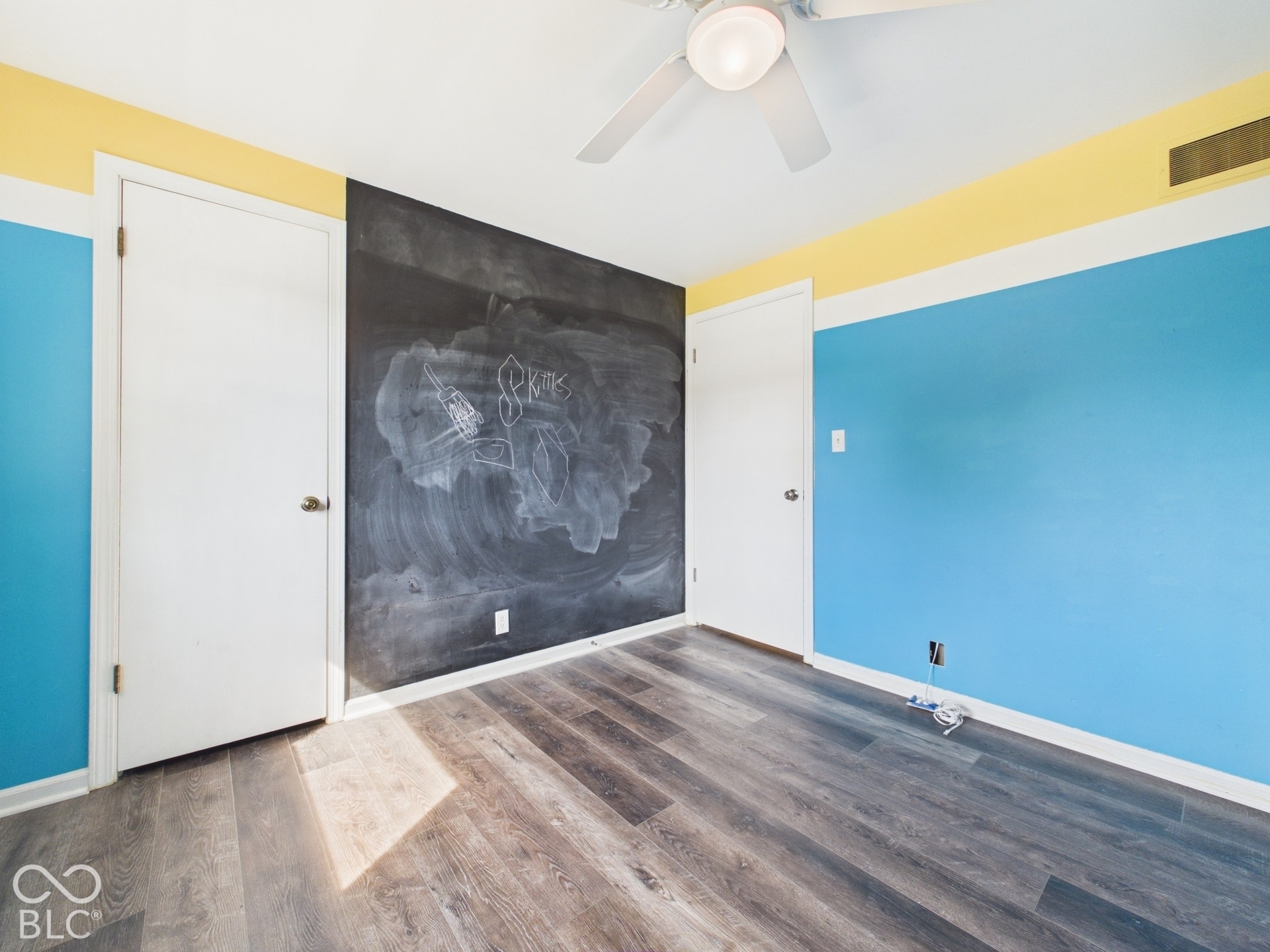 Wood-finish flooring, ceiling fan, and chalkboard wall