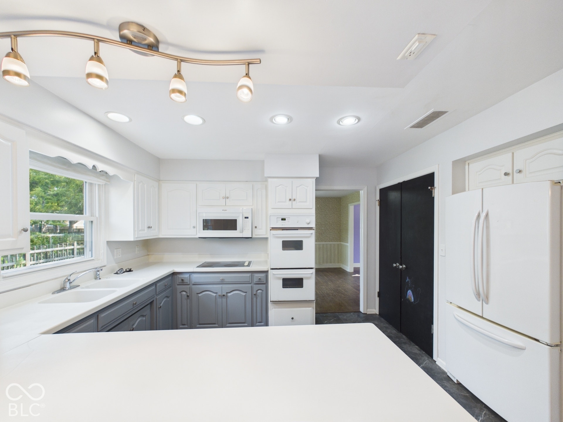 Kitchen featuring recessed lighting, a track lighting fixture, white upper cabinetry, gray lower cabinetry, and an integrated double oven