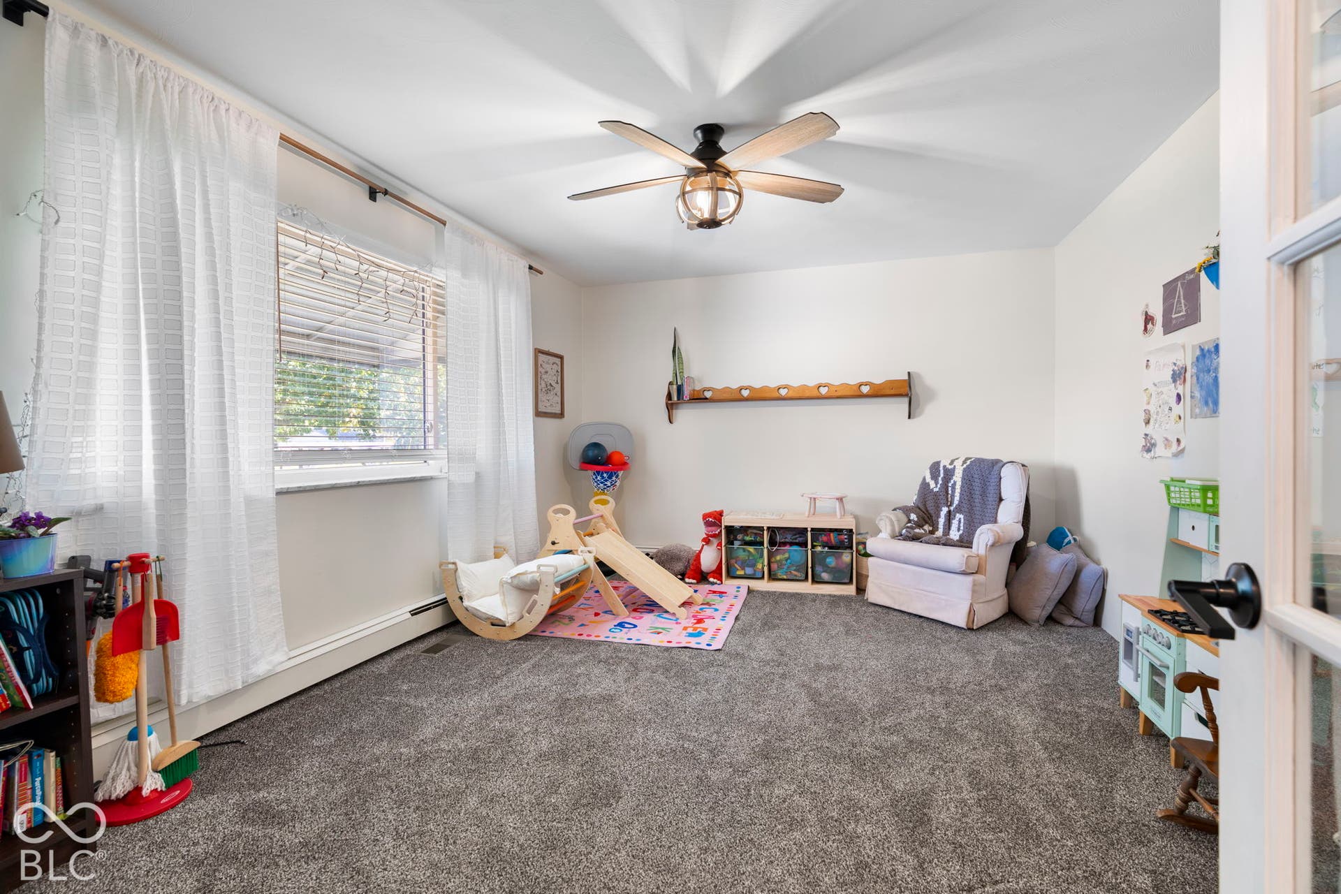 Carpeted room featuring a ceiling fan with light fixture, window with blinds, and white interior walls