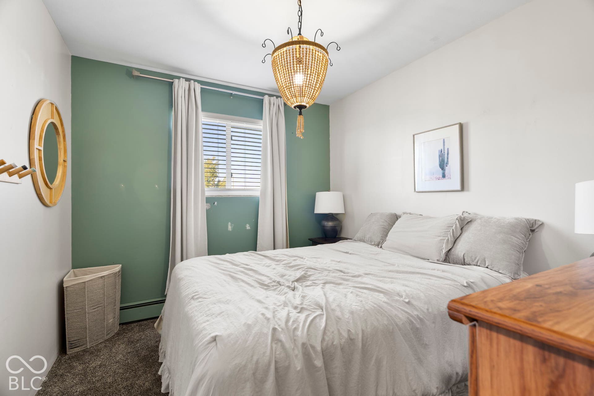 Recessed window with white blinds and drapes, accented wall, textured carpet flooring, and a unique beaded chandelier