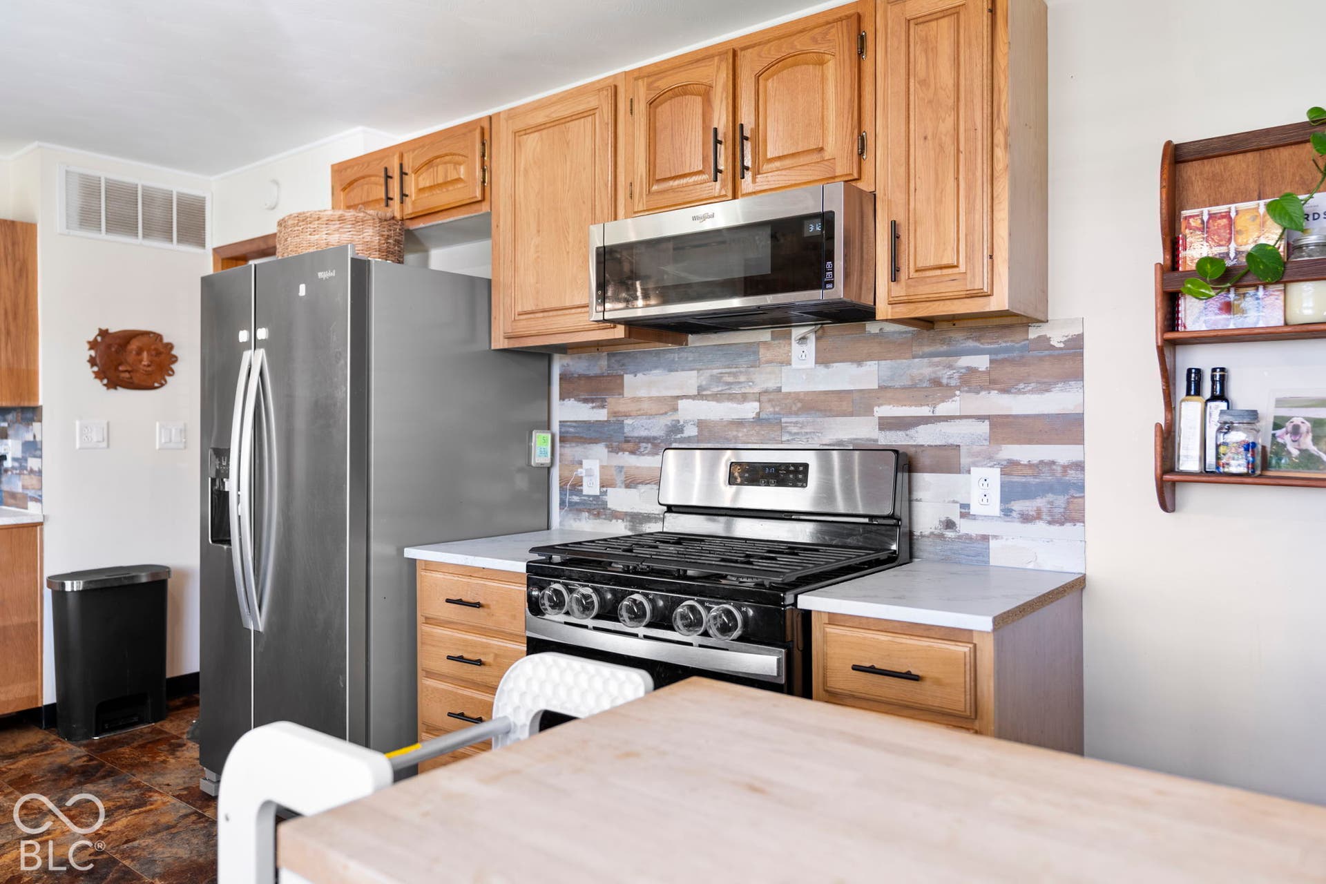 Stainless steel appliances, wood cabinetry, light-toned countertops, and a decorative tile backsplash