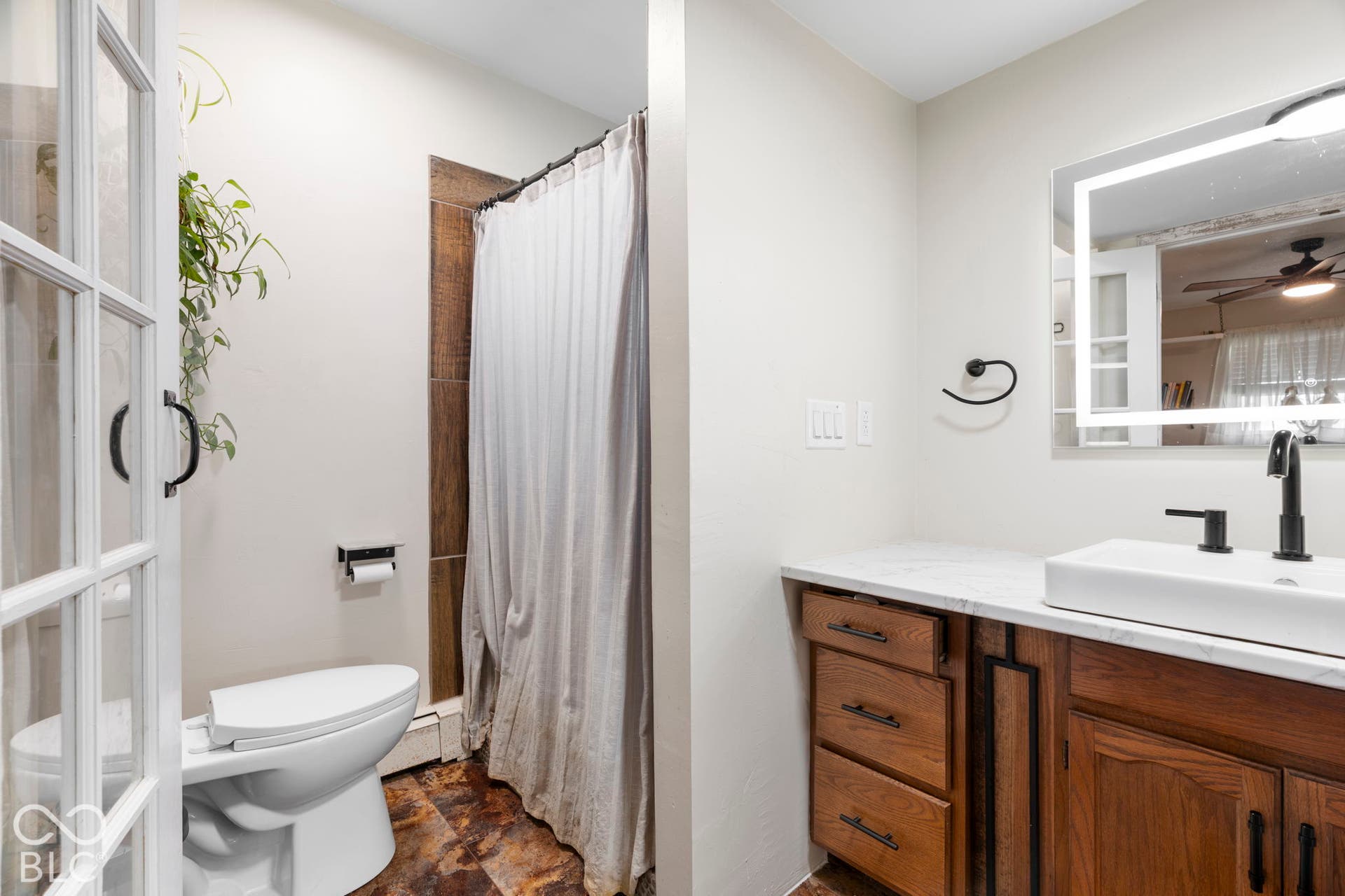 Modern bathroom featuring warm wood-finish cabinetry with multiple drawers, a white quartz countertop, and an undermount sink