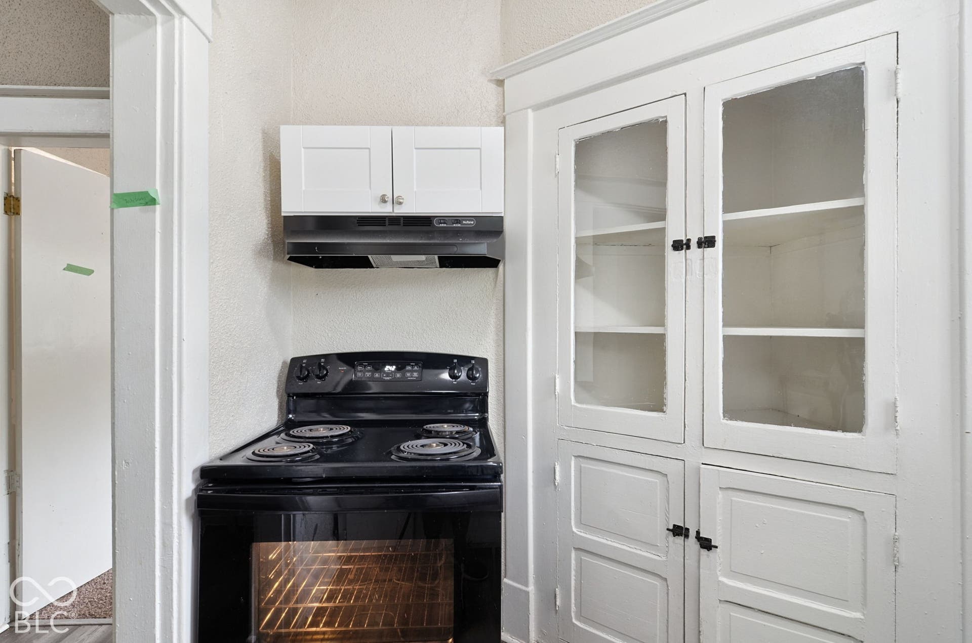 Black electric range with overhead cabinetry and vent hood