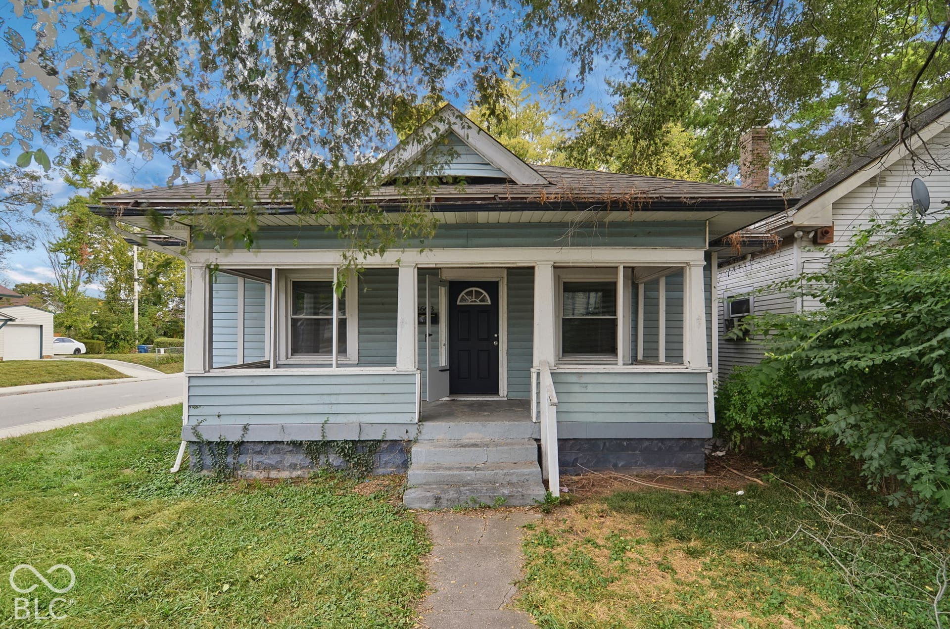 Blue siding exterior with white trim, dark entry door, and a front porch