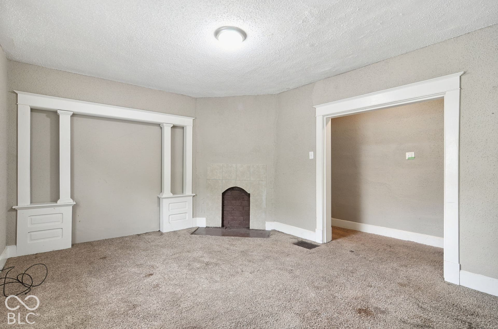 Room featuring carpet flooring, decorative wall trim, and a fireplace with a dark hearth