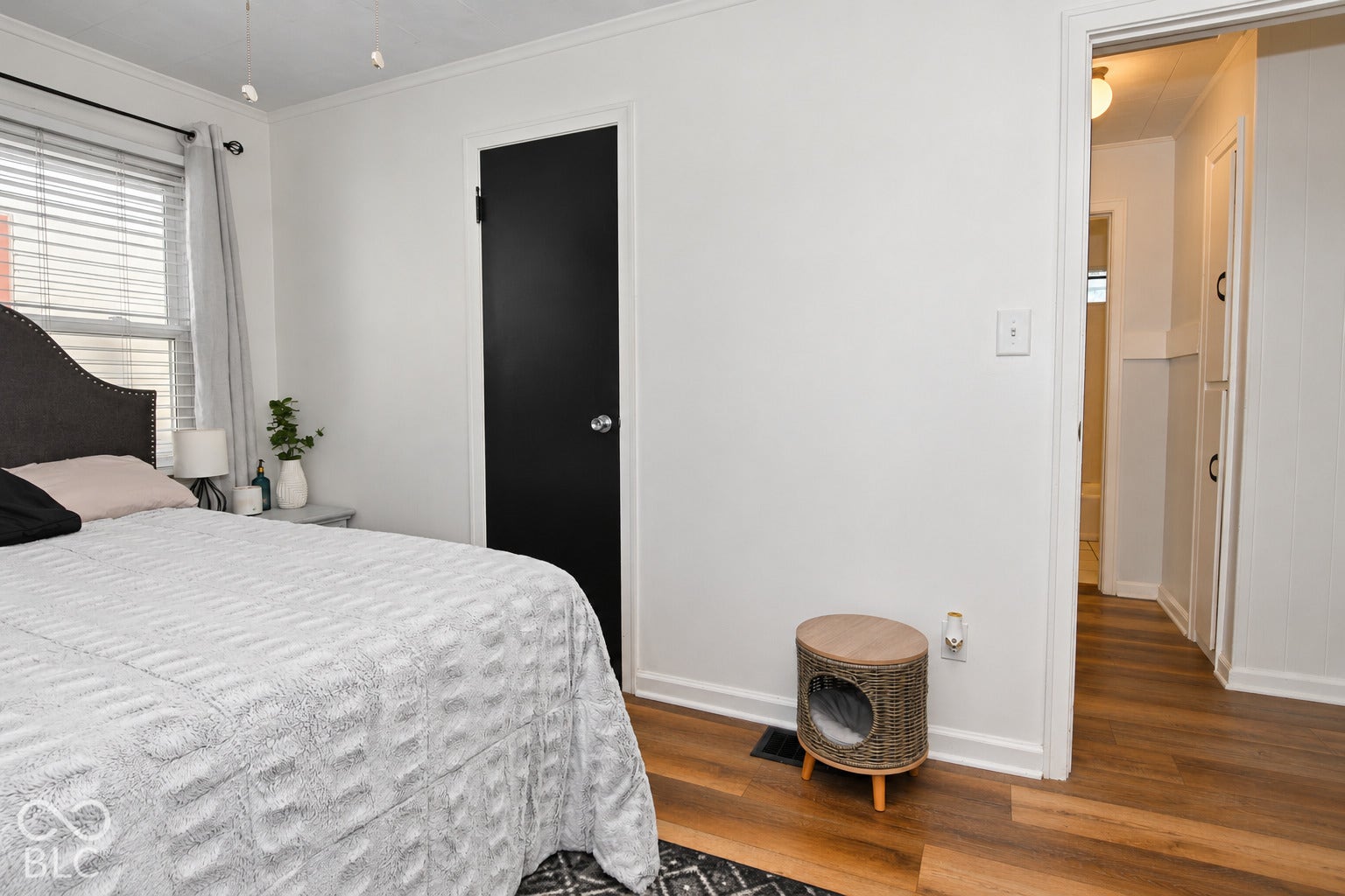 White walls with crown molding, dark wood-finish flooring, a black interior door, and a built-in hallway cabinet