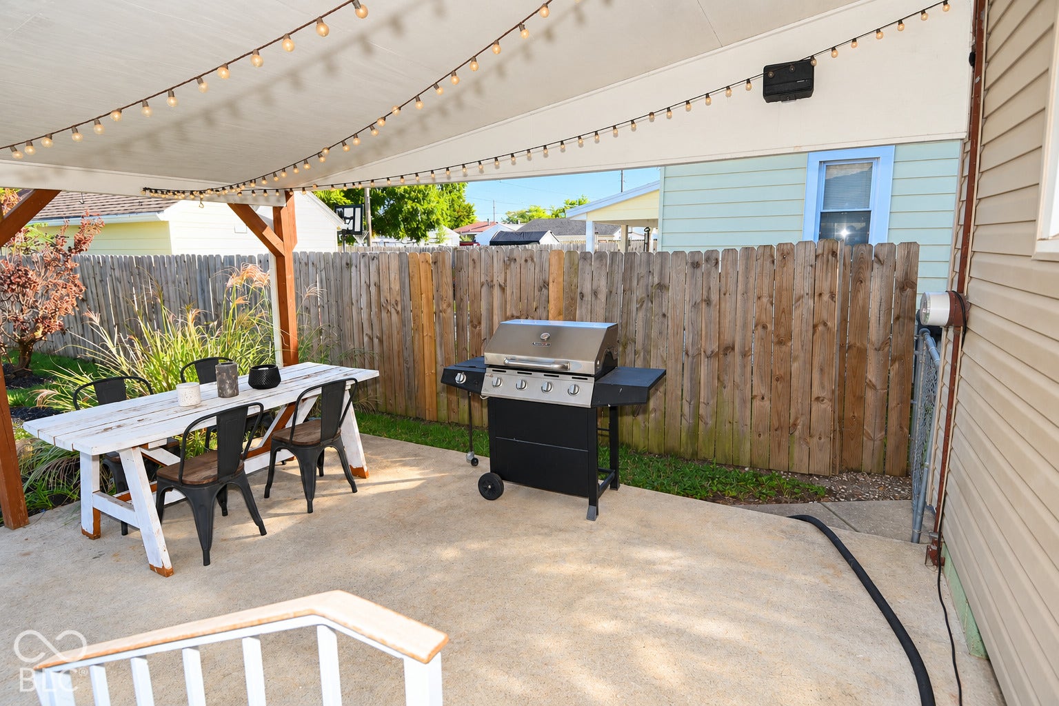 Paved patio area featuring a wooden pergola with a fabric canopy, and string lighting