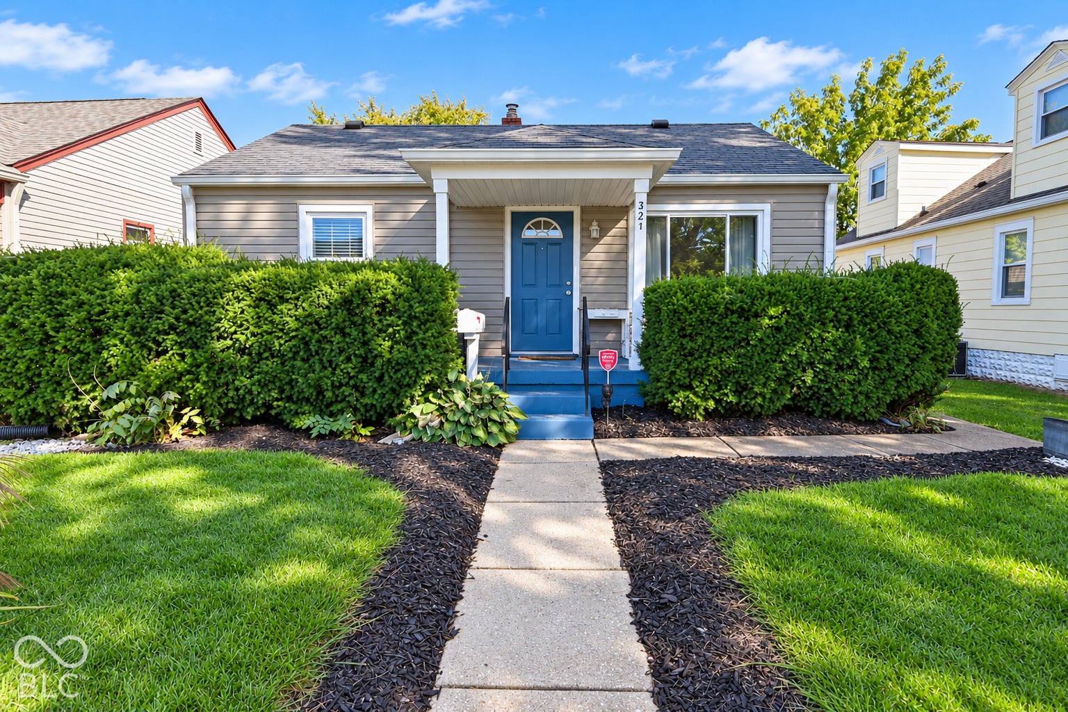 Single-story residence featuring siding exterior, a front entry with a blue door, a covered porch, and a concrete walkway