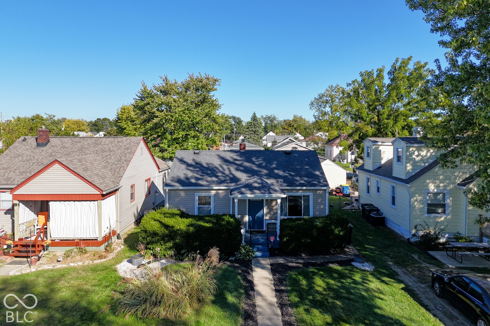 Siding exterior with a covered porch, mature landscaping, and an established lawn