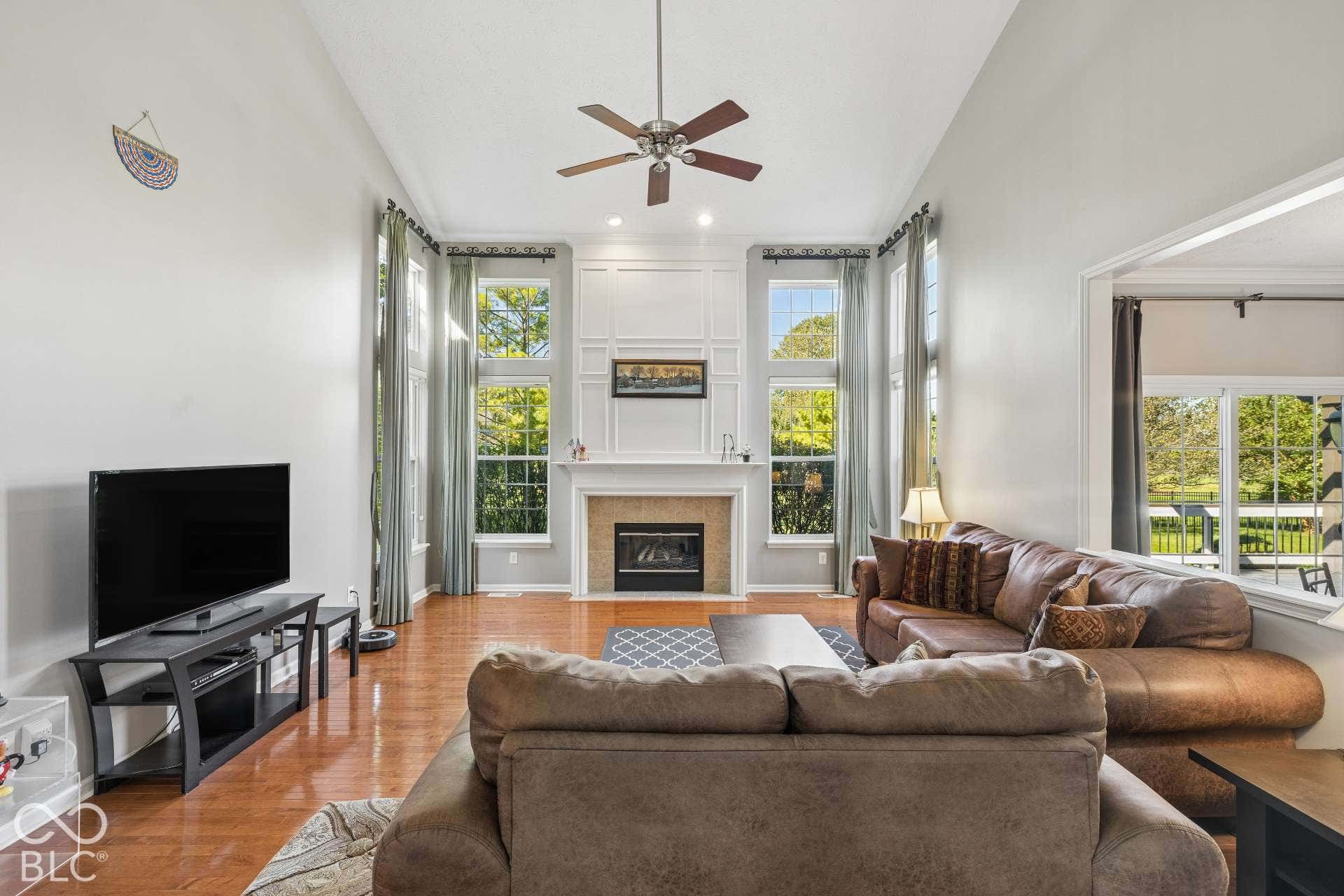 The fireplace anchors this spacious gathering area while tall windows bring the outdoors in.