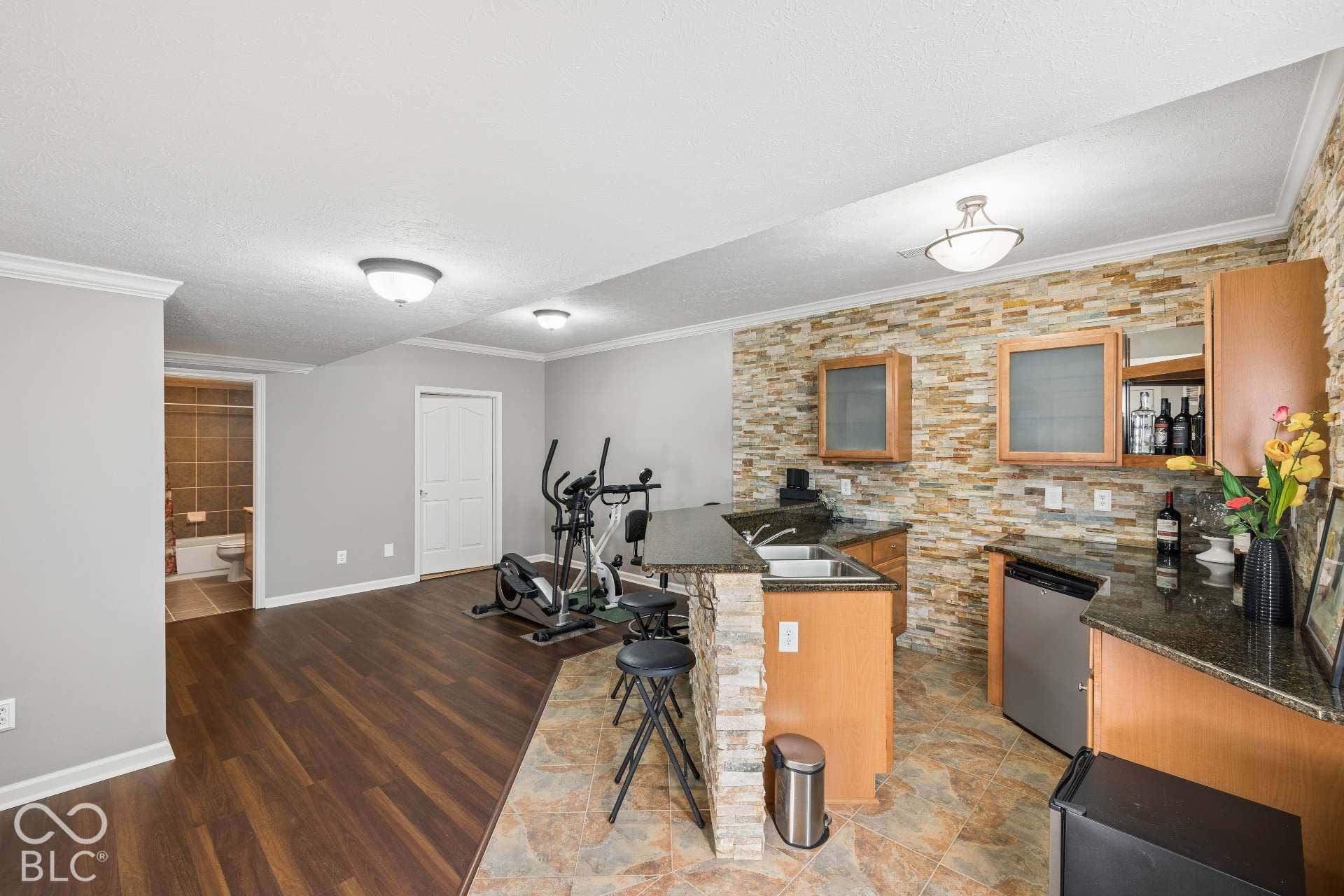 Wet bar with cabinetry and seating makes the finished basement ready for game days, movie nights and entertaining.