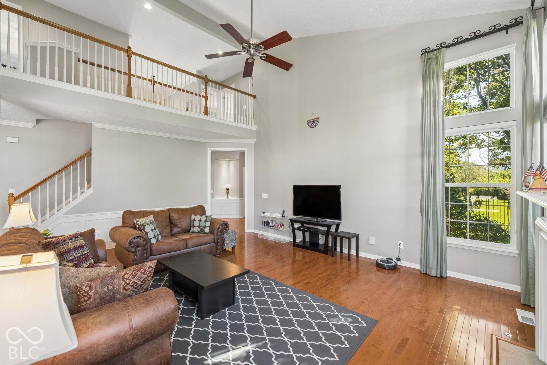 Two-Story Great Room. Soaring ceilings, a fireplace and walls of windows create a bright and inviting gathering space.