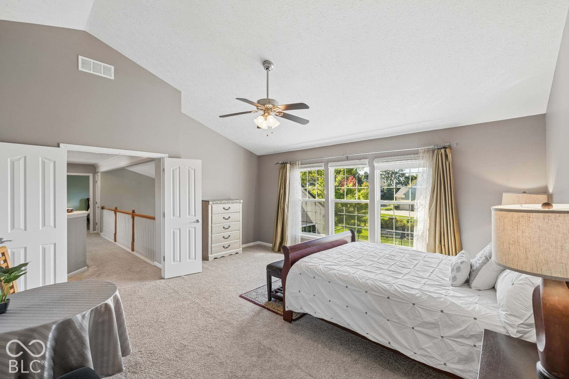 Another view highlights the generous size of the primary bedroom and its wall of windows overlooking the backyard.