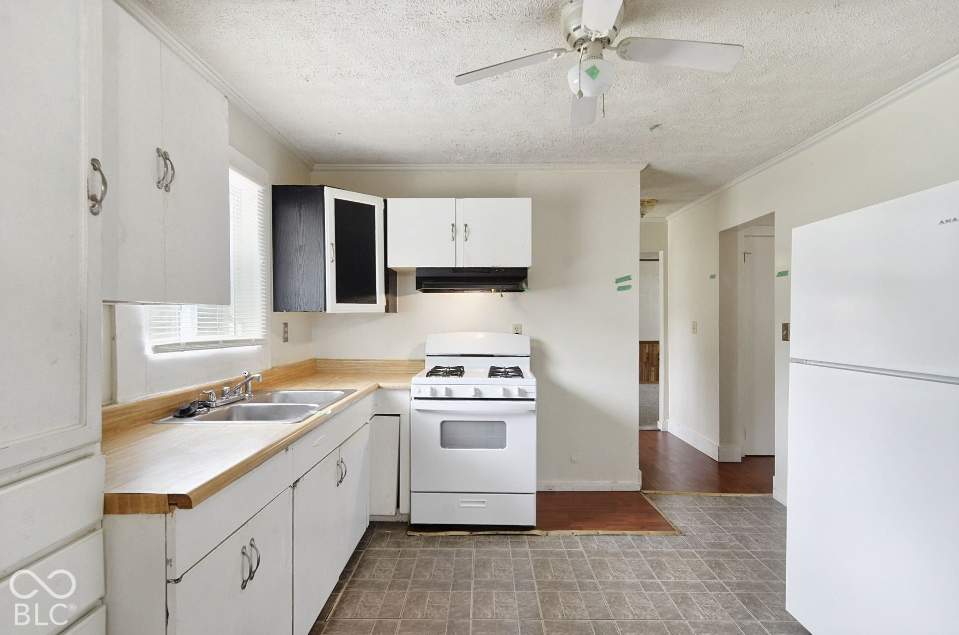 Kitchen featuring white cabinetry, a double basin stainless steel sink, wood-finish countertops, a gas range, and a ceiling fan