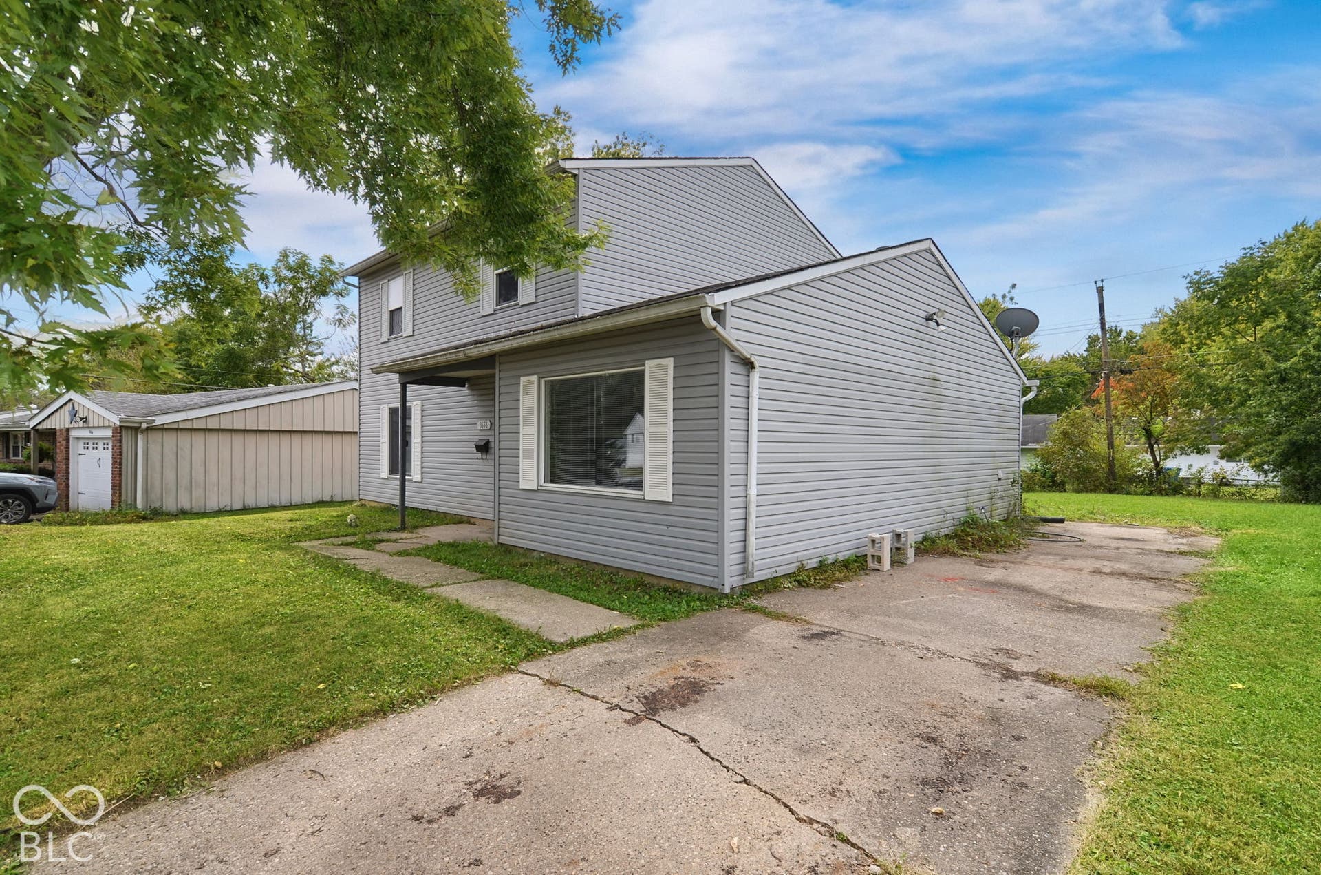 Two-story residence with light gray siding, white window shutters, and a covered entry