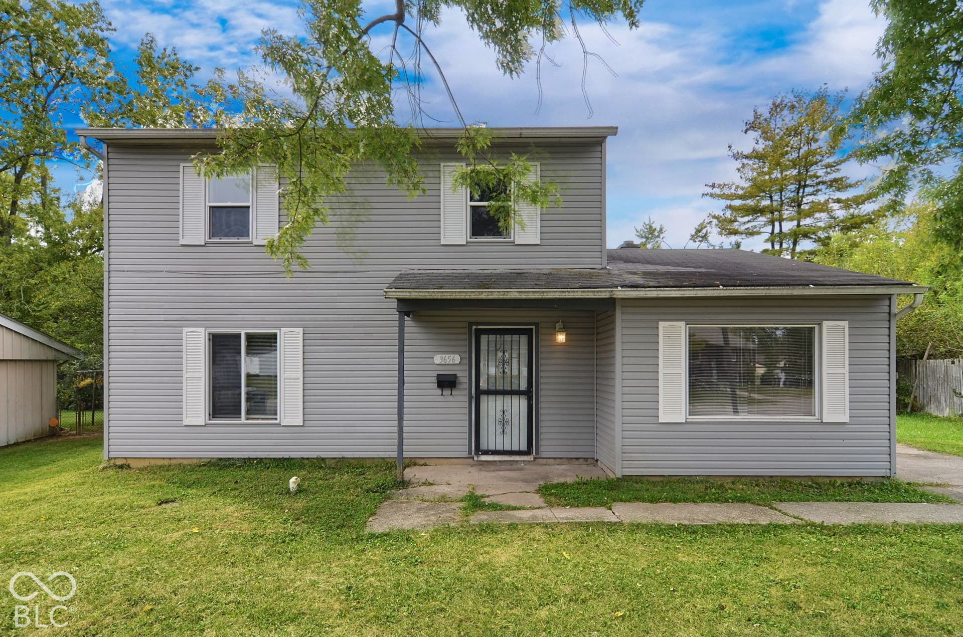 Two-story residence featuring gray siding, a covered entry, and white window shutters